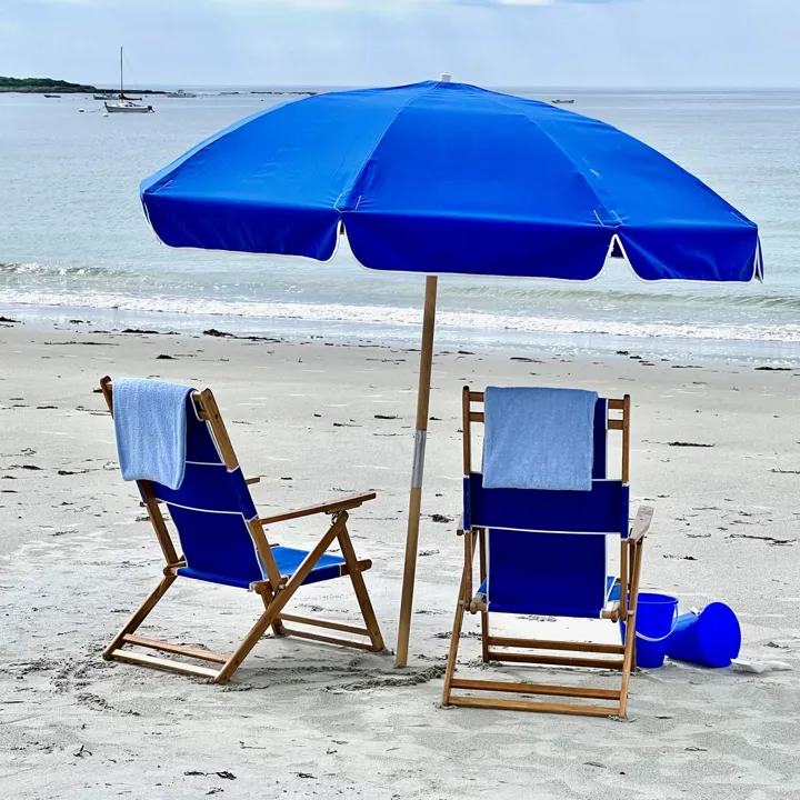 Blue Beach Chairs And Umbrella On The Beach With The Occean In The Background